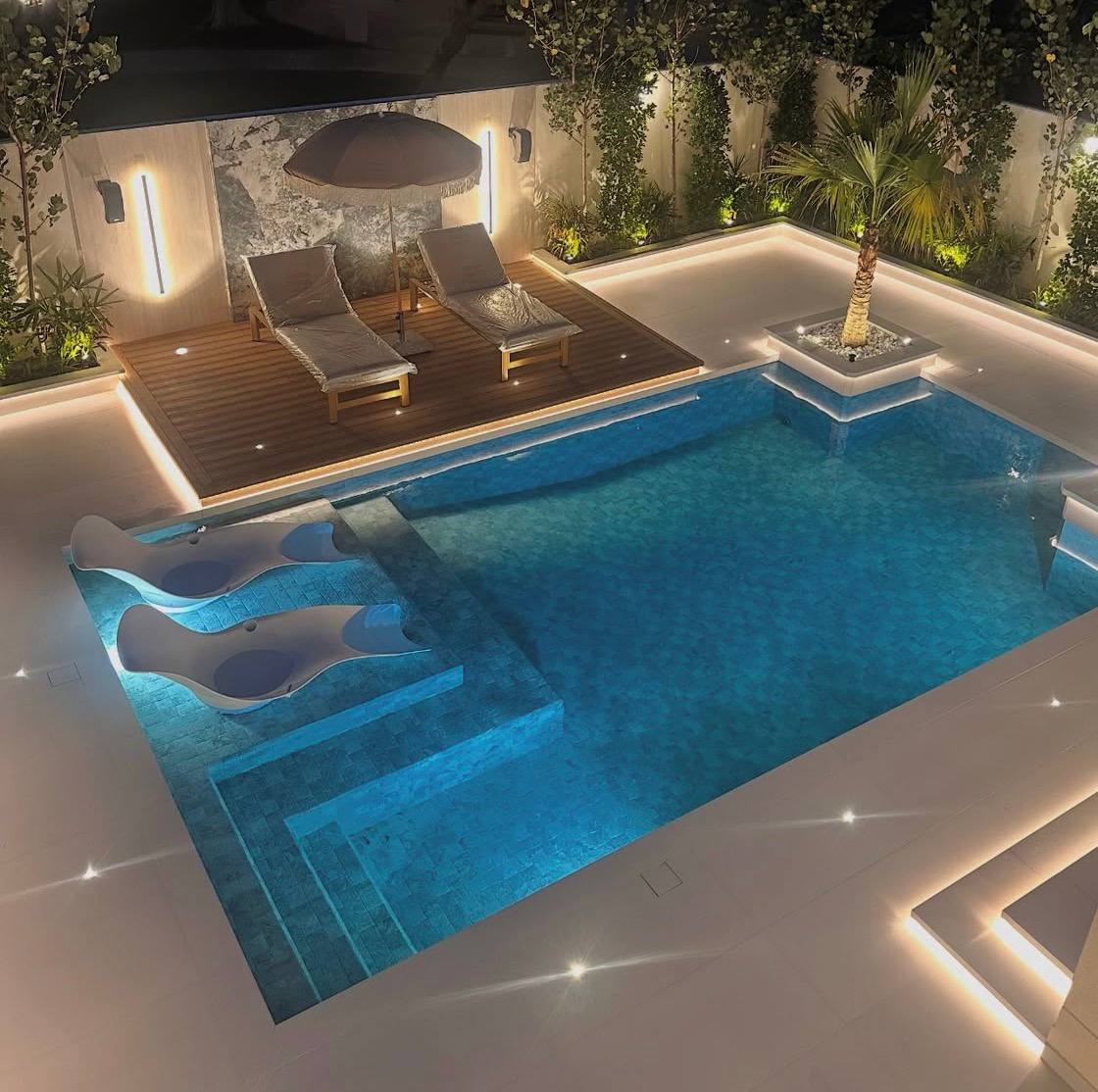 Night pool with LED lighting and lounge chairs